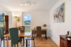 Un comedor con una mesa de madera, sillas verdes, una lámpara y vistas al exterior.
