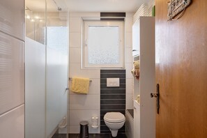 Une salle de bain avec des toilettes, une fenêtre, une serviette et une poubelle.