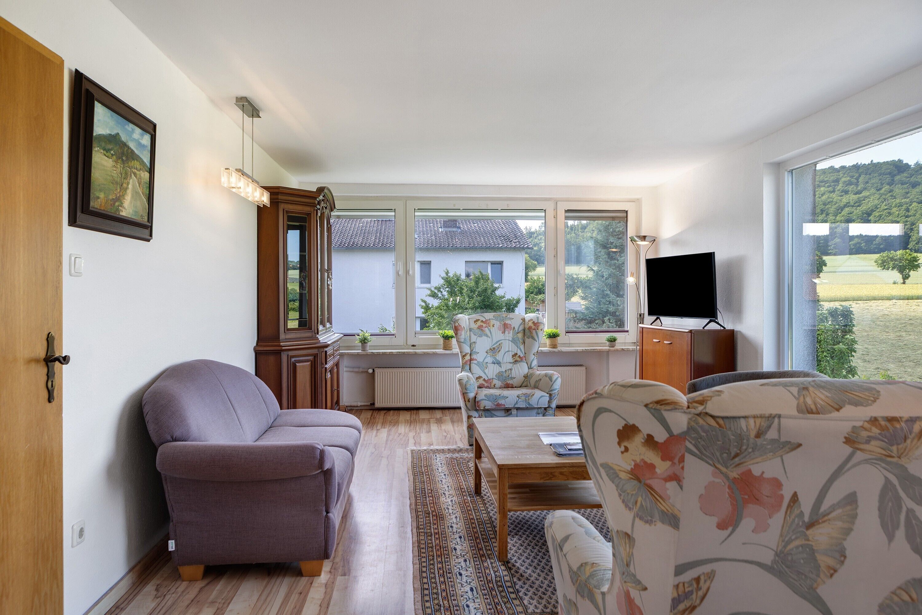 Ein Wohnzimmer mit einer Couch, einem Sessel, einem Couchtisch und einem Fernseher.
