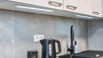 A modern kitchen with a kettle, a coffee maker, and a sink.