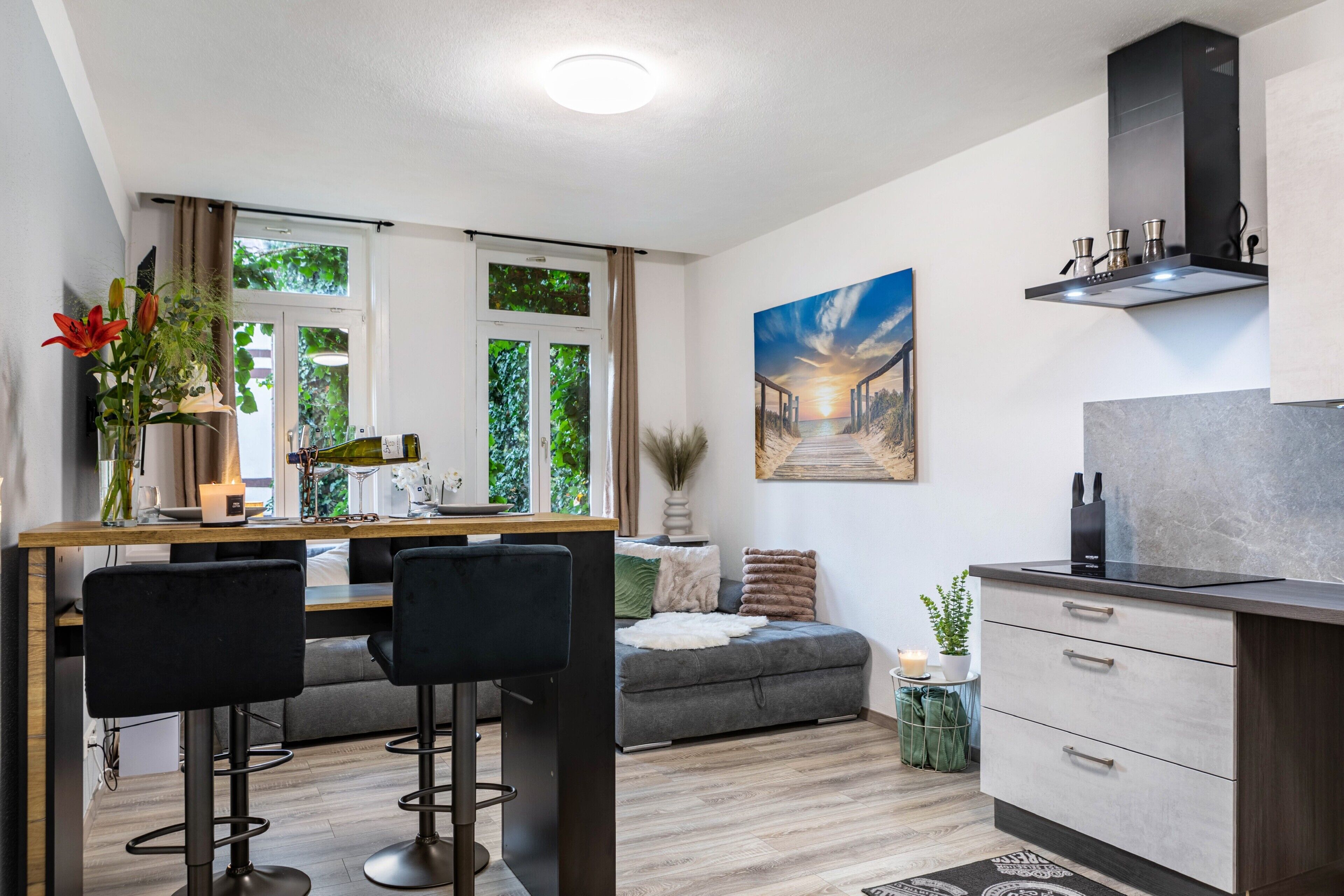 A modern kitchen with a dining area, bar stools, and a sofa.