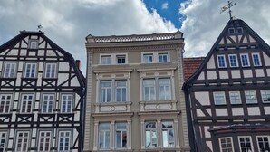 A row of traditional European buildings with a central building featuring large windows and a sign that reads 'Carl Ramspeck.' - Apartment 'Marktplatz Ferienwohnung' with Wi-Fi (Alsfeld)