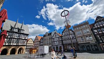 A cobblestone square with historic buildings, a fountain, and a signboard.