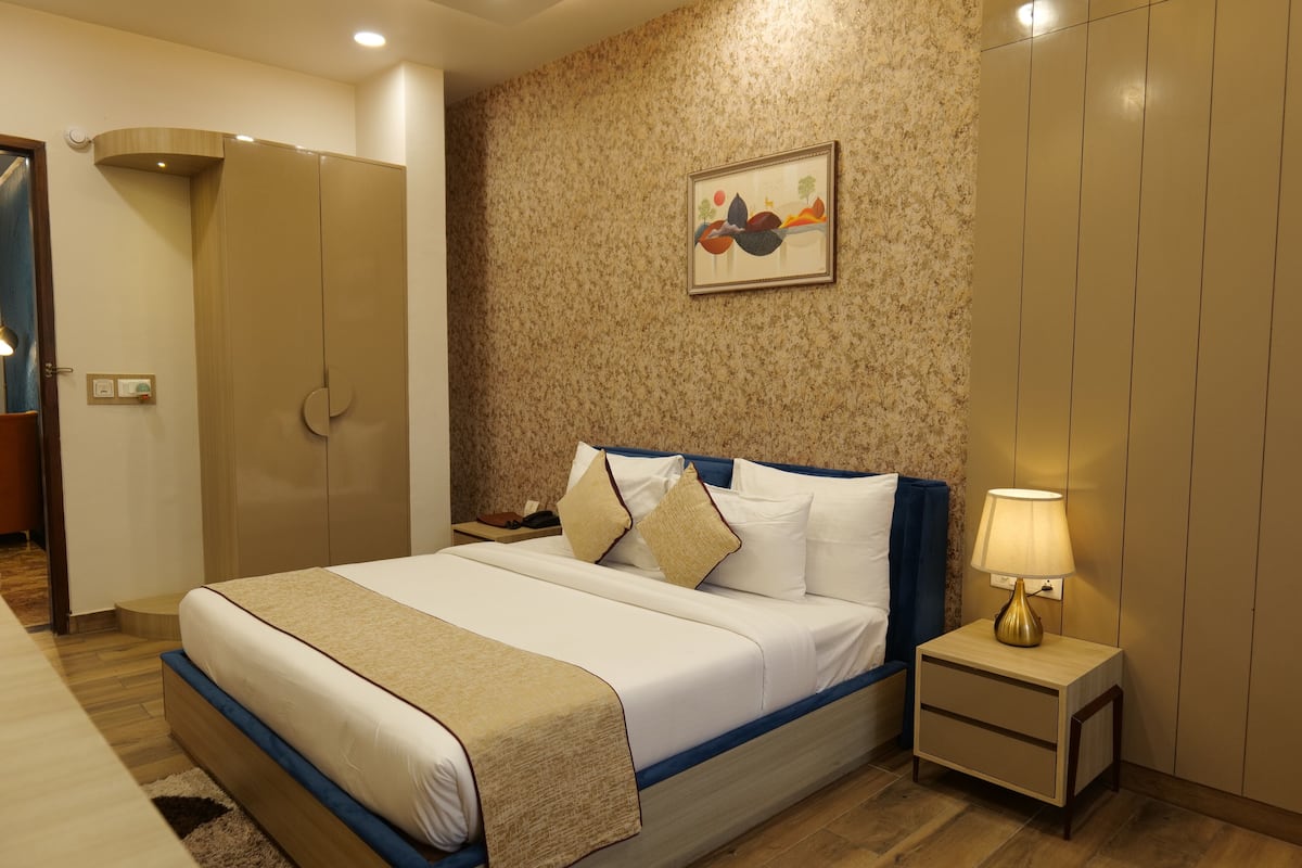 Quarto bem arrumado com cama, mesa de cabeceira e uma obra de arte na parede.