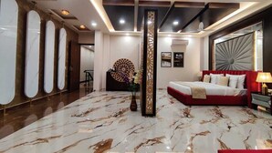 Un moderno vestíbulo de hotel con piso de mármol, un sofá rojo y una gran columna decorativa.