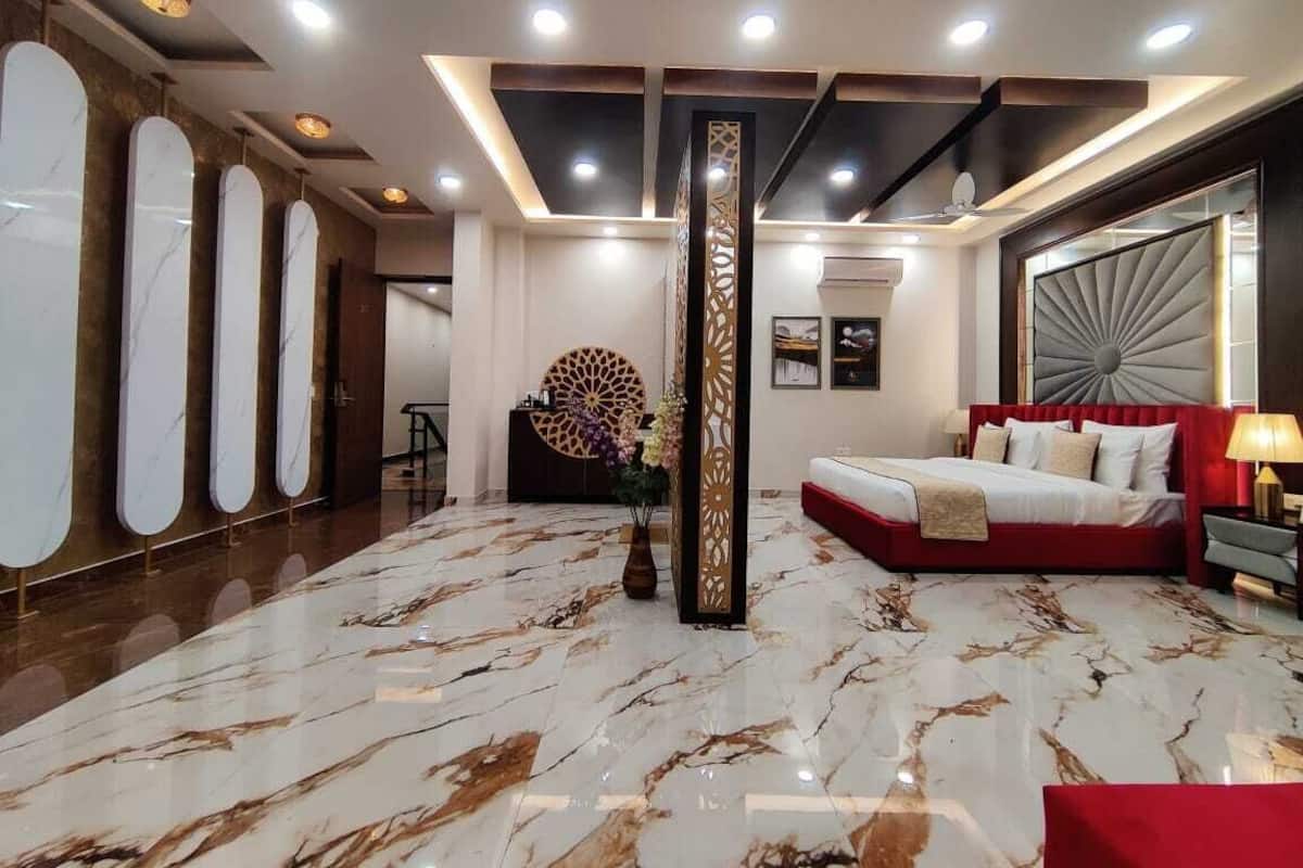 Um hall de hotel moderno com piso de mármore, um sofá vermelho e um grande pilar decorativo.