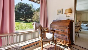 A room with a wooden chair, a dresser, a radiator, and a view of a garden. - Holiday Home with Mountain View, Large Terrace and Wi-Fi (Baden-Baden)