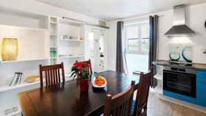 Una cocina moderna con armarios de madera, una mesa de comedor, sillas y un horno empotrado.