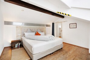 A bedroom with a large bed, wooden flooring, a built-in bookshelf, and a skylight.
