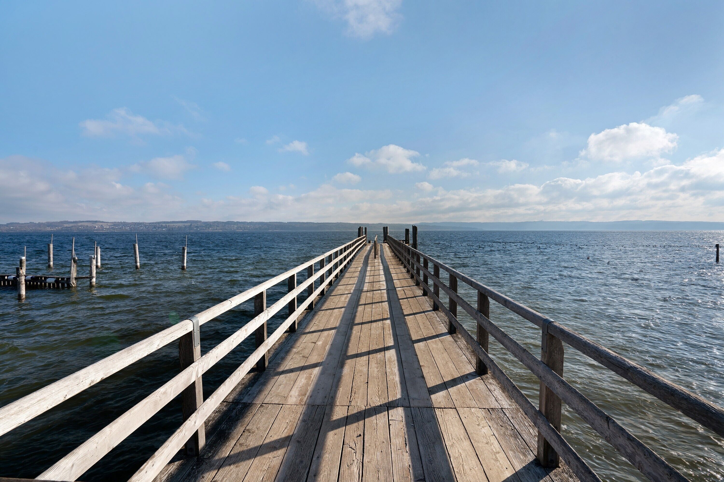 Un muelle de madera que se adentra en aguas tranquilas bajo un cielo despejado.