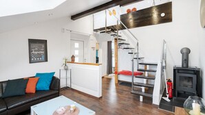 Una sala de estar moderna con una escalera, una chimenea y un comedor.