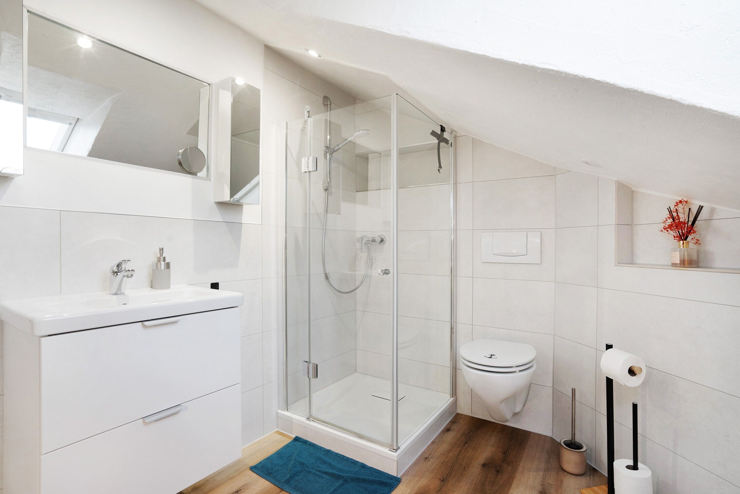 A modern bathroom with a glass shower enclosure, a white sink, and a toilet.