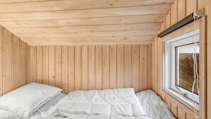 Une pièce de cabane en bois comprenant un lit, une fenêtre et un plafond en bois.