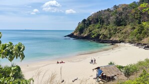 Une plage à l’eau turquoise et limpide, bordée d’un rivage sablonneux et d’une végétation luxuriante.