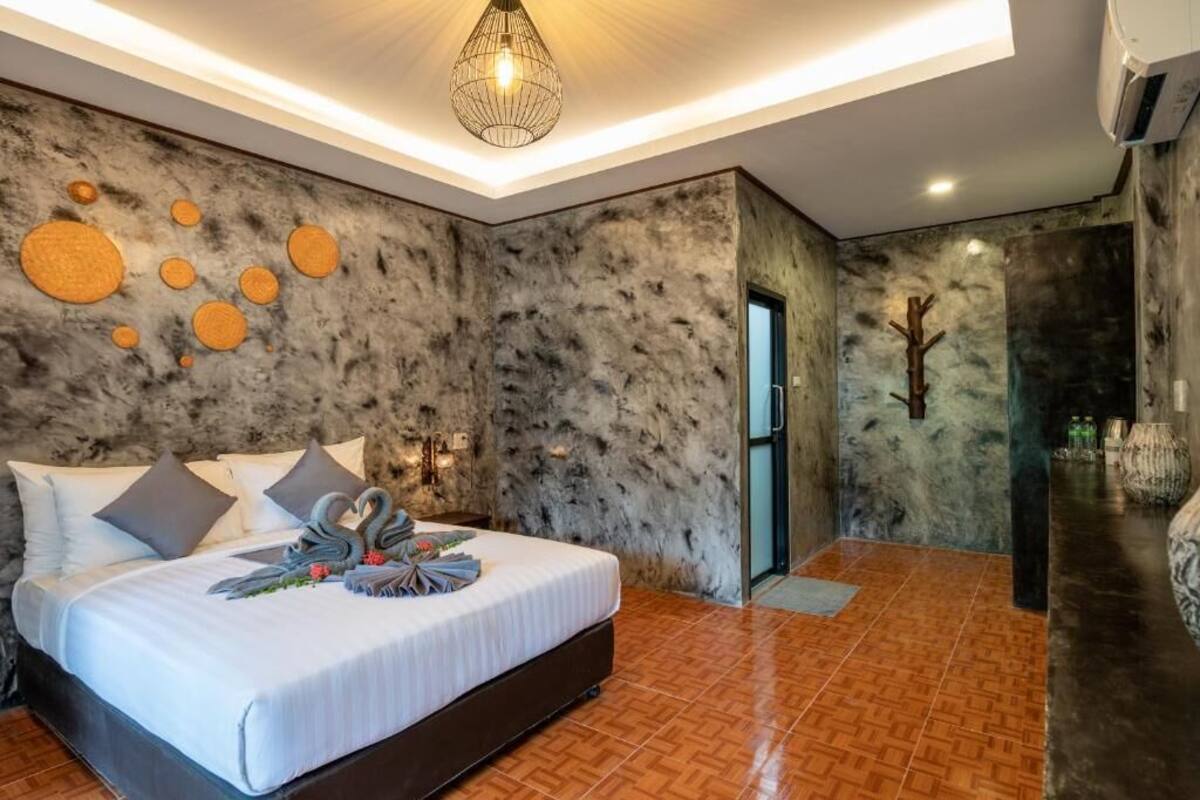 A modern bedroom with a marble wall, a bed with decorative swan pillows, a unique light fixture, and a wooden floor.