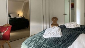 A hotel room with a bed, a chair, a wooden chair, a door, and a bathroom visible through an open door. - Vacation home Hirschle -Sauna, dogs, 3 bedrooms, 8 persons (Alpirsbach)