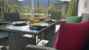 An outdoor dining area with wicker furniture, a table set for two, and a large umbrella providing shade. - Vacation home Hirschle -Sauna, dogs, 3 bedrooms, 8 persons (Alpirsbach)