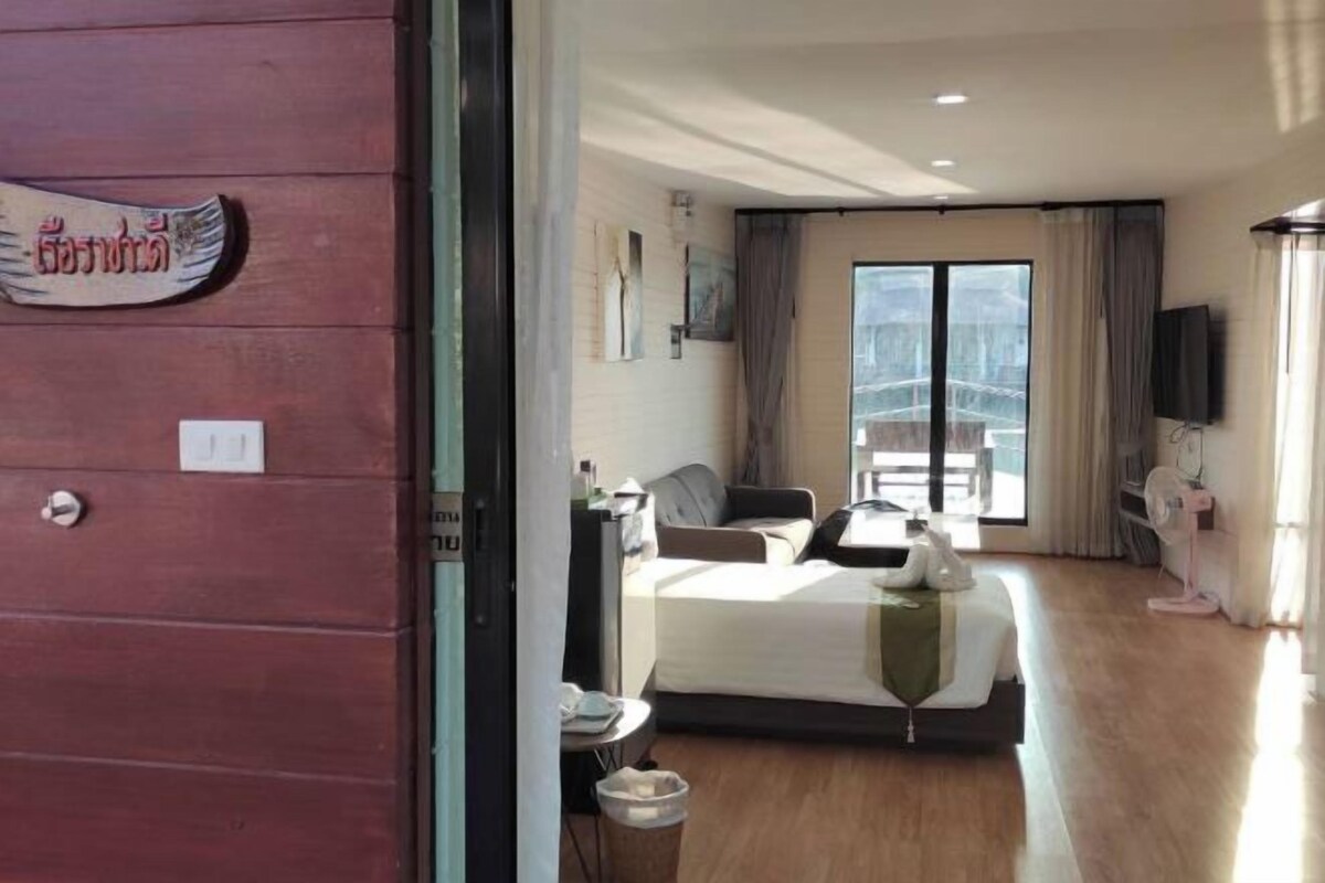Ein Hotelzimmer mit Bett, Schreibtisch, Stuhl, Fernseher und einem Fenster mit Vorhängen.