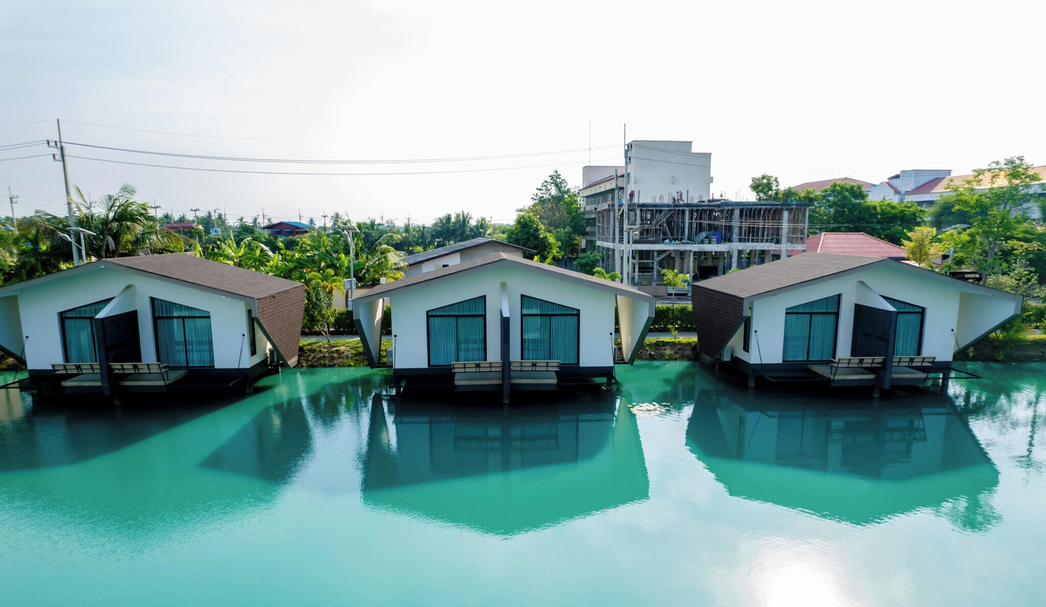 Three overwater bungalows with a clear view of the water and surrounding greenery.