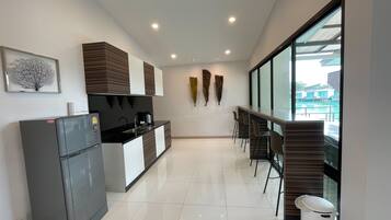 Una cocina moderna con refrigerador, estufa y lavaplatos. Hay un comedor con sillas y una mesa. La habitación tiene ventanas amplias y vista a una piscina.