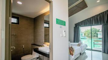 A bathroom with a shower, toilet, and sink. There is a sign on the wall and a window with curtains.
