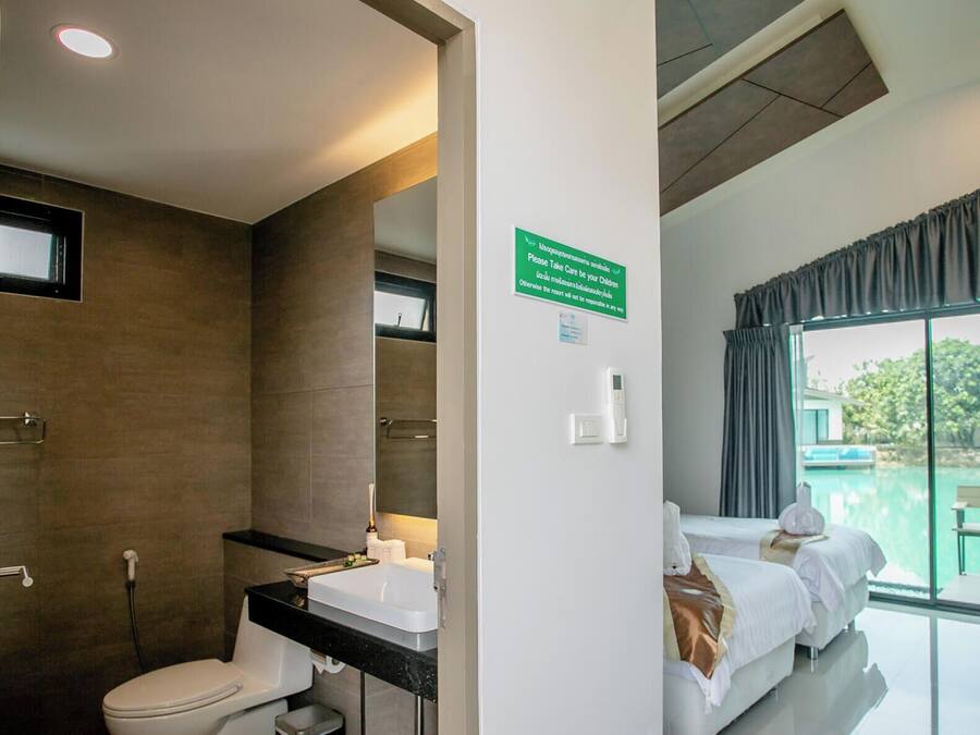 A bathroom with a shower, toilet, and sink. There is a sign on the wall and a window with curtains.