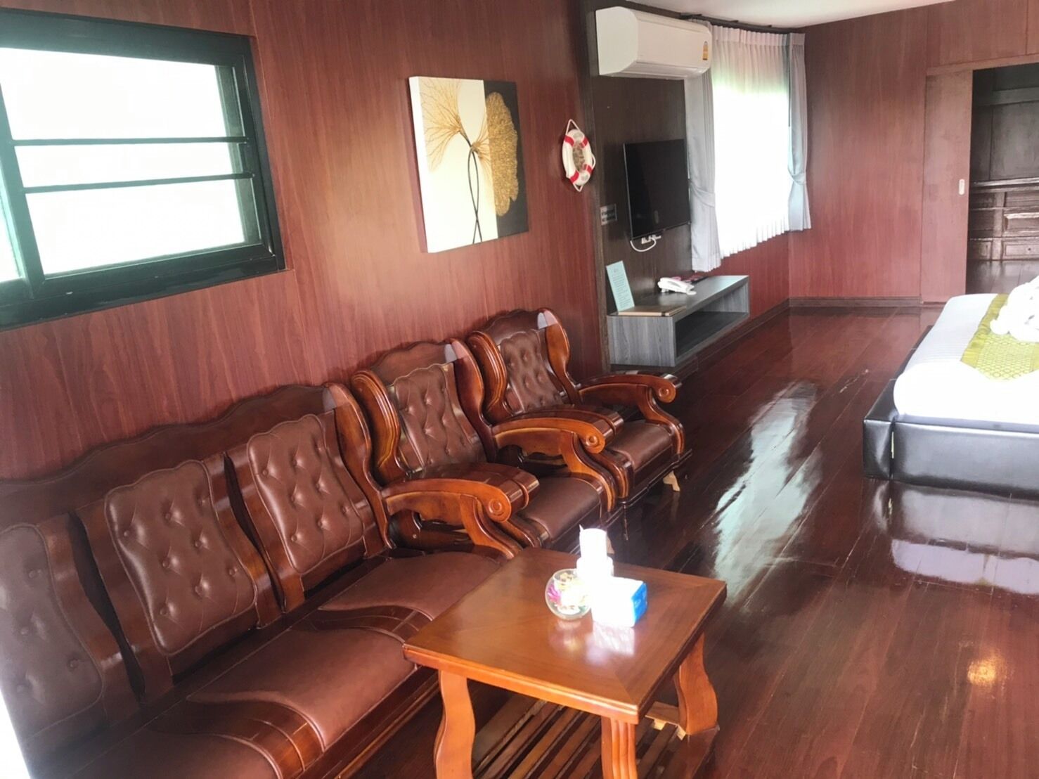A room with a sofa set, a small table, a television, and a bed.