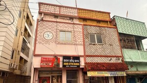 A multi-story building with a patterned facade, several commercial signs, and a visible staircase. - Goroomgo Anand Atithi Bhawan Puri (Puri)