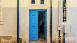 A blue door leading to a staircase inside a building with a textured wall and a utility box on the right. - Bica's River View Duplex (Lisbon)