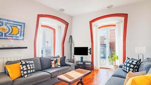 A living room with a grey sofa, a wooden coffee table, and a TV on a stand. - Bica's River View Duplex (Lisbon)