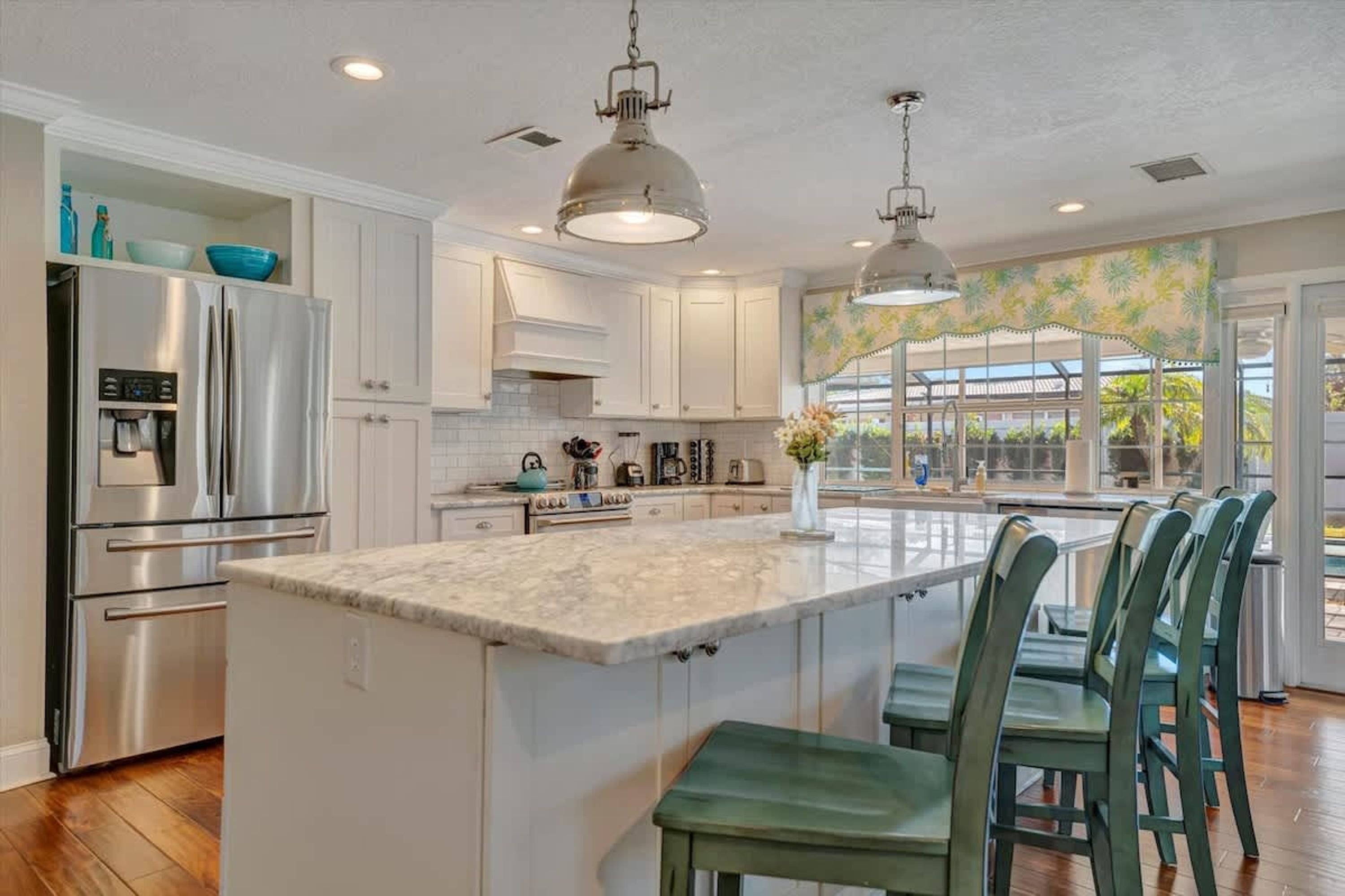A modern kitchen with white cabinets, stainless steel appliances, and a large island with bar stools.