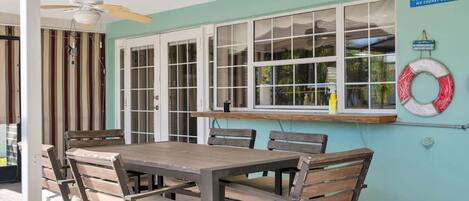 A dining area with a table and chairs, a ceiling fan, and a window with a view of greenery.