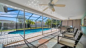 Amplia zona de piscina interior con techo de cristal, suelo de baldosas y ventilador de techo.