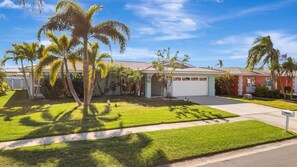 A residential house with a well-maintained lawn, palm trees, and a garage. - The Crown House 4b Pool Home 6 Mins to IR Beach (Largo)