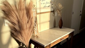 Une table en bois, sur laquelle est posé un panneau indiquant « BIENVENUE » et de l’herbe des pampas.