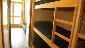 Un dormitorio con literas y una puerta que da a un pasillo.