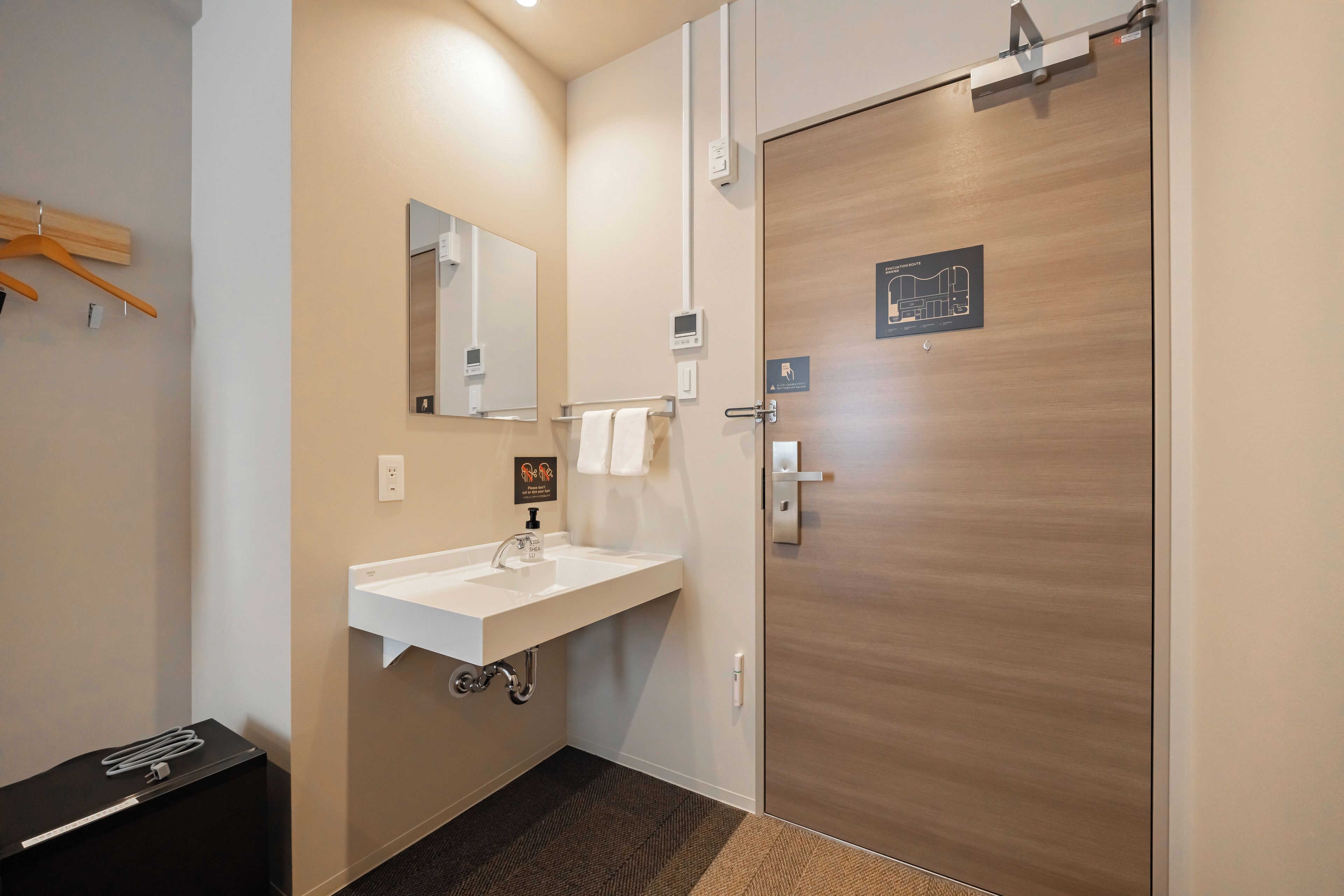 A modern bathroom with a white sink, mirror, and towel rack.