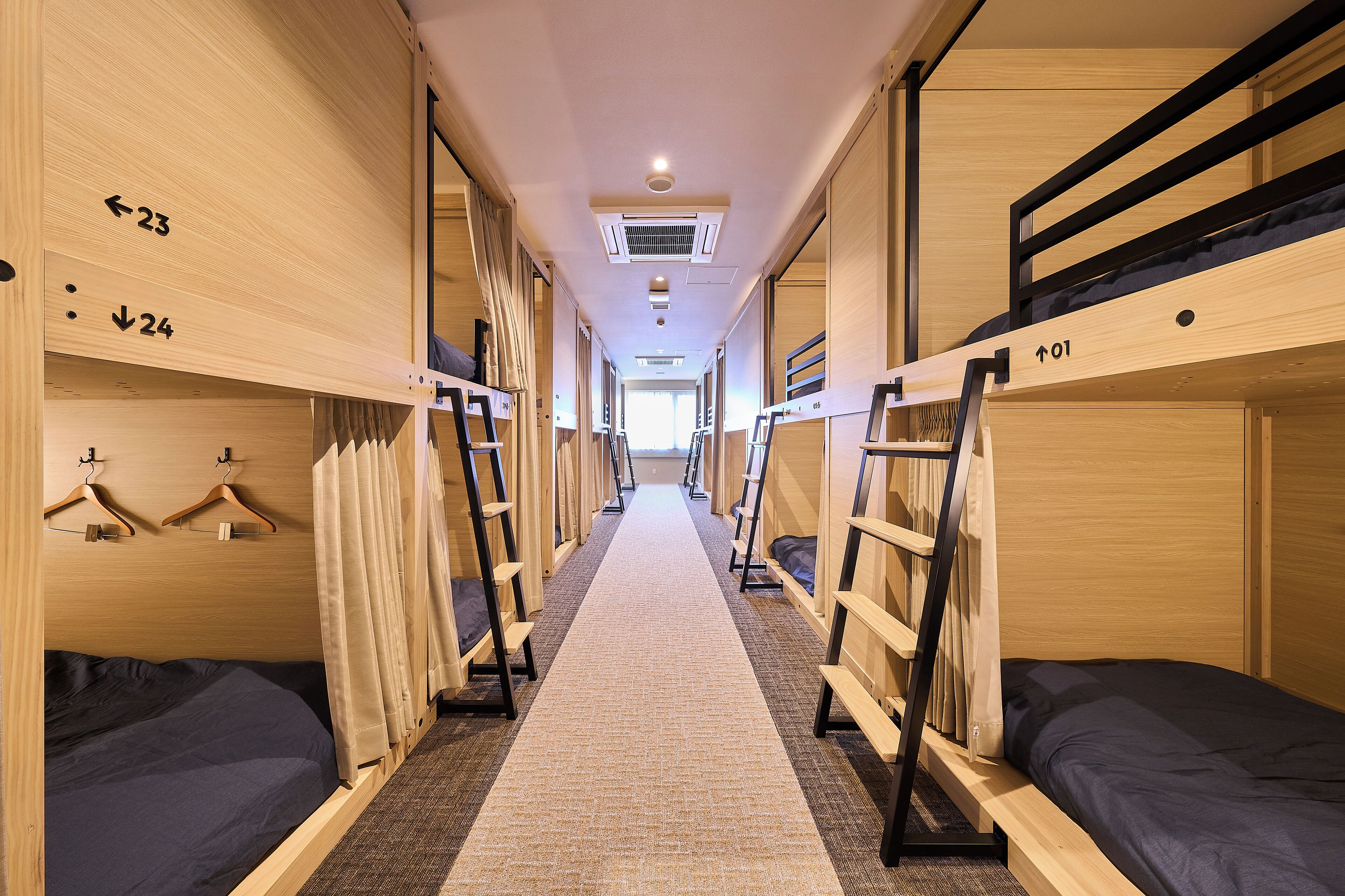 A corridor with bunk beds, numbered doors, and a carpeted floor.