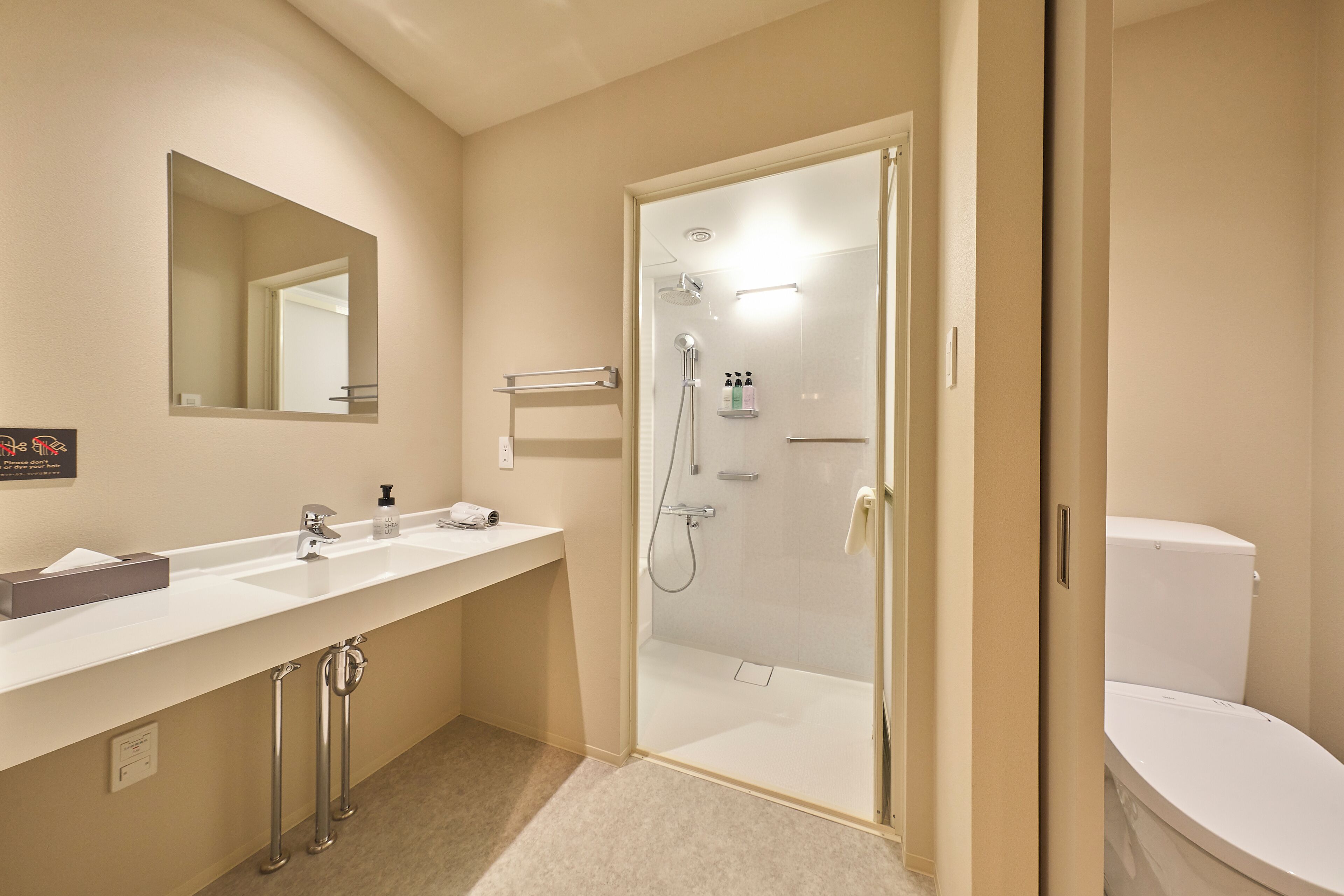 Un baño moderno con ducha de vidrio, lavamanos blanco con espejo y un inodoro.