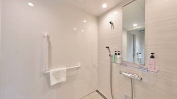 A modern bathroom with a glass shower enclosure, a white towel rack, and a mirror with a shelf holding toiletries.