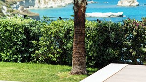 A palm tree in a landscaped area with a pool and a view of the sea and hills in the background. - Miraida Exclusive Residence (Apokoronos)