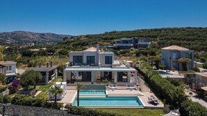 A modern villa with a swimming pool, a covered patio, and a view of the surrounding hills. - Miraida Exclusive Residence (Apokoronos)