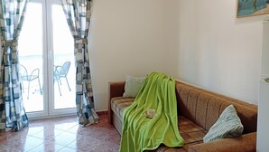 Un salon avec un canapé, une couverture verte et un tableau accroché au mur.