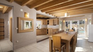 A spacious kitchen with wooden beams, a large dining table, and a view of a swimming pool. - Villa Chiara with a private pool and sauna (Premantura)