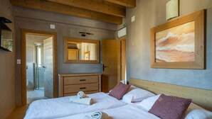 A hotel room with two beds, wooden headboards, a large mirror, and a painting on the wall. - Villa Chiara with a private pool and sauna (Premantura)