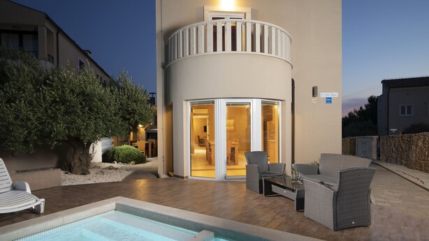 A pool area with a hot tub, outdoor seating, and a building with a balcony. - Villa Chiara with a private pool and sauna (Premantura)