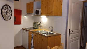 Ett kompakt kök med träskåp, en diskho i rostfritt stål och en mikrovågsugn.