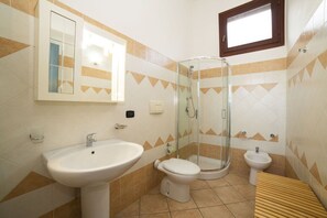 A bathroom with a sink, toilet, bidet, and a glass shower enclosure.