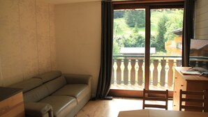 Et værelse med en sofa, et træbord og udsigt til en balkon med gelænder.
