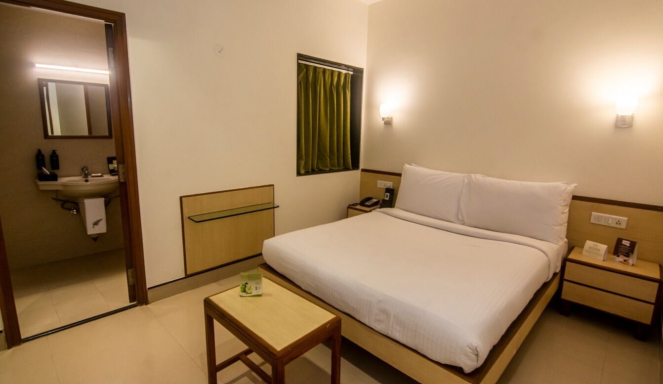 Una habitación de hotel con cama, mesita de noche y espejo.